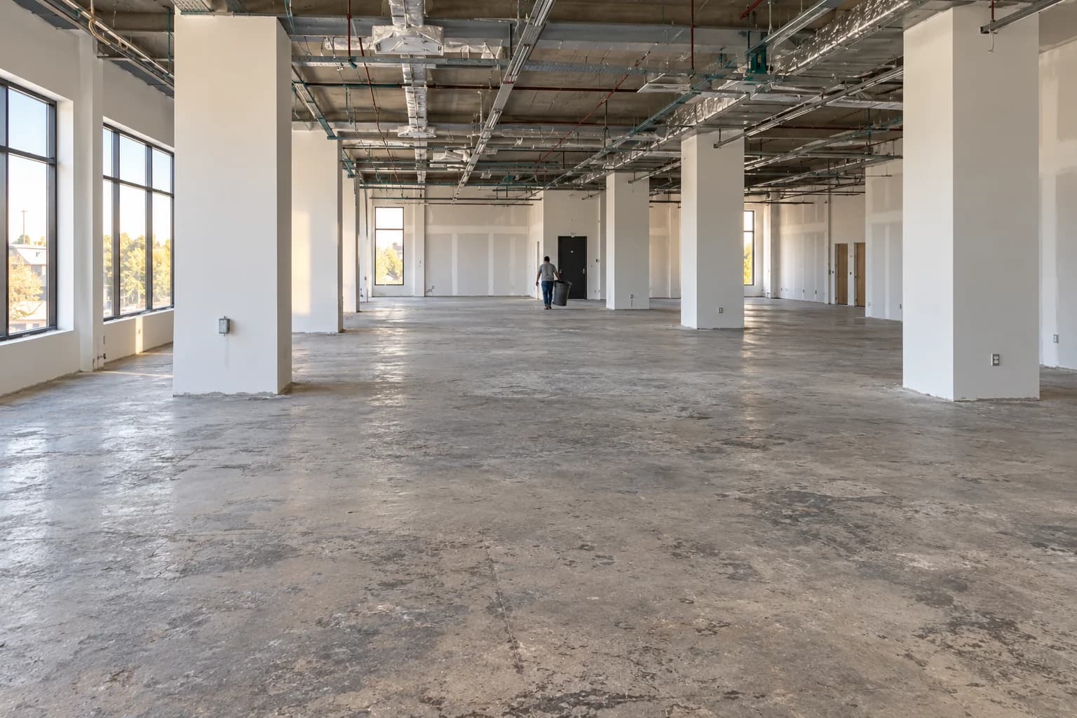 Generated after example: the same commercial interior from a closer angle, with clear worn concrete and a worker leaving with a bin